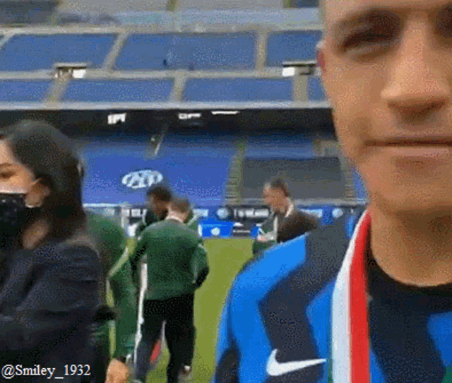 a man with a medal around his neck is standing in front of a stadium