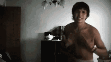 a shirtless man is standing in a dark room .