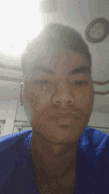 a young man in a blue shirt looks at the camera
