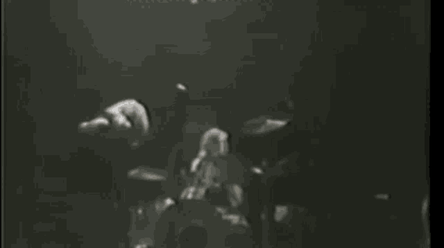 a black and white photo of a man playing a guitar on a stage .