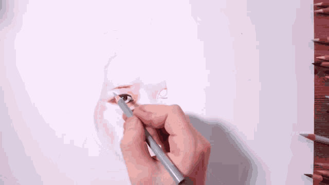 a person is drawing a woman 's eye with a pencil on a piece of paper .