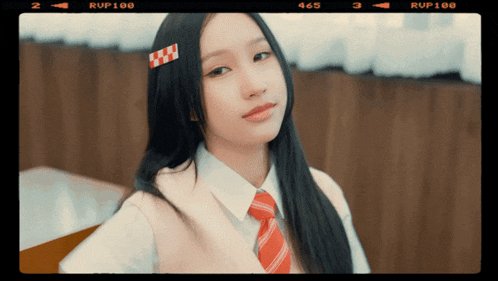 a girl wearing a white shirt and a red tie has rup100 written on the bottom