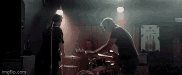 a man playing drums in a dark room with a sign that says ' imgflip.com ' on the bottom
