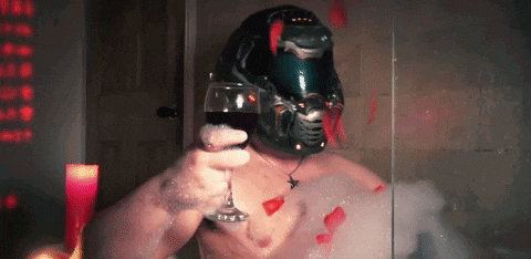 a man in a helmet is holding a glass of wine in a bathtub