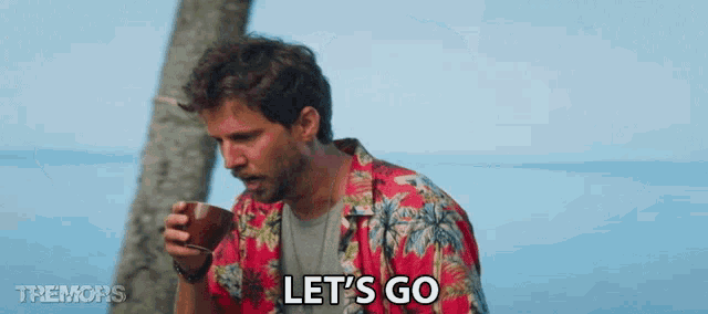 a man in a hawaiian shirt is drinking from a cup and saying let 's go .