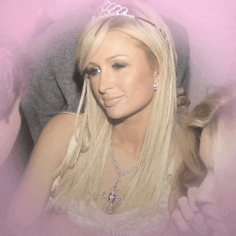 a woman wearing a tiara and a cross necklace is smiling