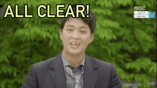a man in a suit and tie is standing in front of a tree and says `` all clear '' .
