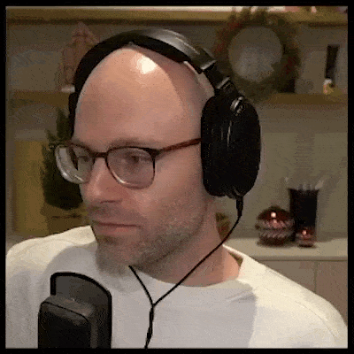 a bald man wearing glasses and headphones is looking at the camera .