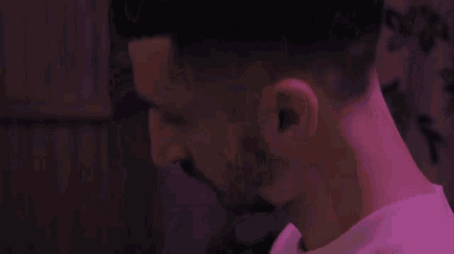 a close up of a man 's neck and ear in a purple light .