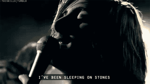 a man singing into a microphone with the words " i 've been sleeping on stones " next to him
