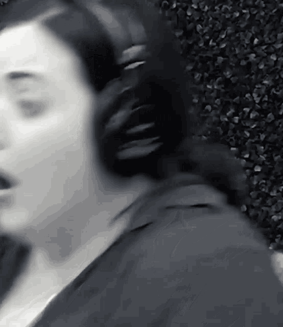 a woman is wearing headphones and singing in a black and white photo .