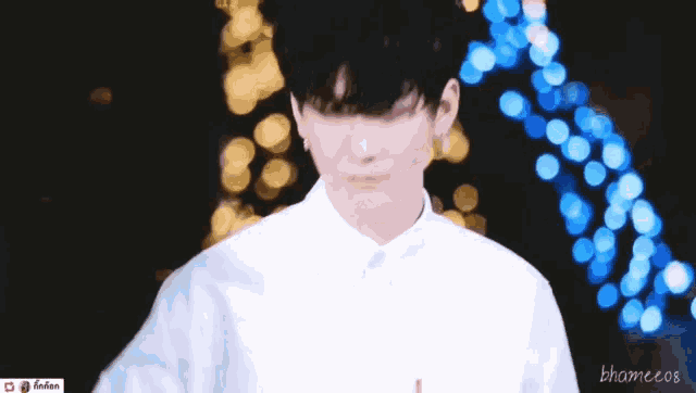 a young man in a white shirt is standing in front of a blurred background .