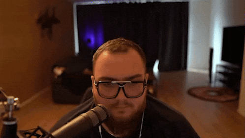 a man with a beard and glasses is sitting in front of a microphone