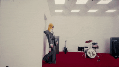a man in a suit is dancing in a room with a red carpet