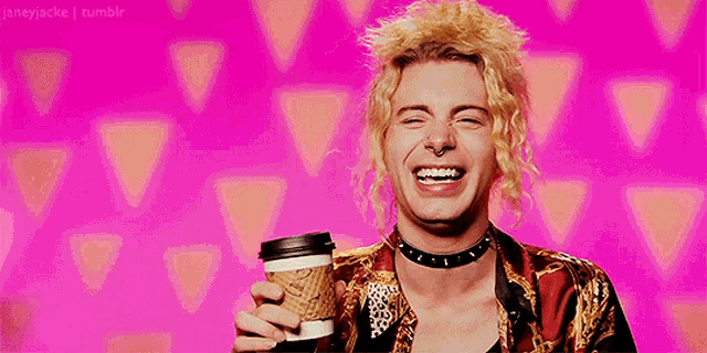 a man with blonde hair is holding a coffee cup and smiling