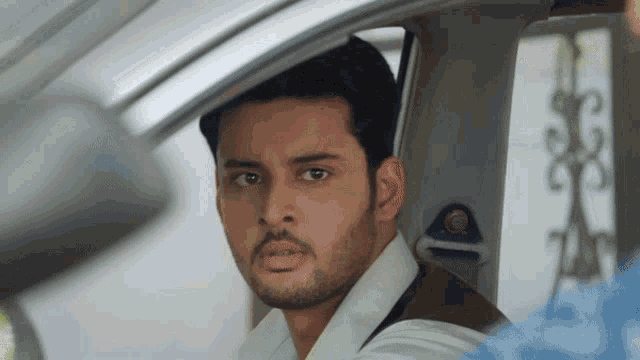a man with a beard is sitting in a car and looking at the camera