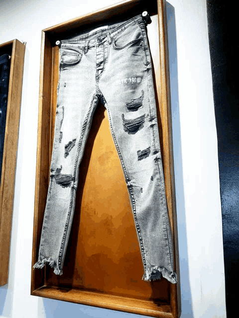 a pair of jeans hanging in a wooden frame with the word proud written on it