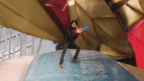 a man is holding a blue toy gun in front of a large robot