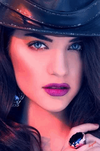 a woman wearing a hat and a ring has purple lipstick on her lips .