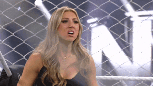 a woman behind a chain link fence with the letter n on the wall behind her