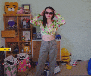 a woman wearing sunglasses and a floral shirt is standing in front of a shelf that has 375 / 400 on it