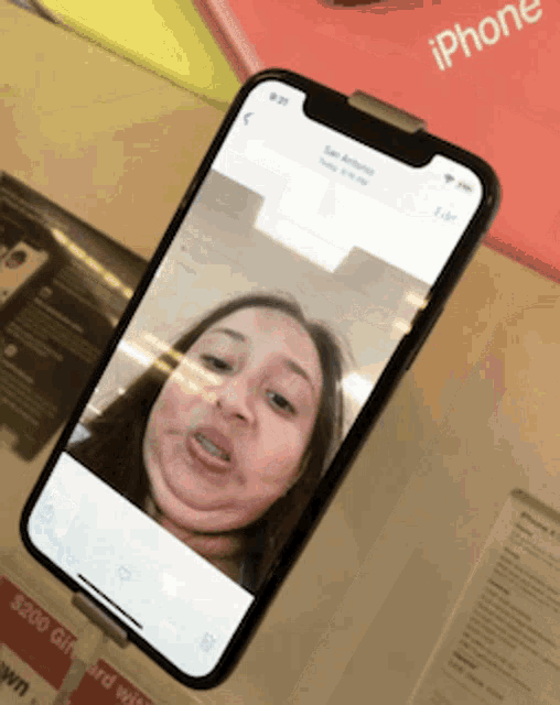 a phone with a picture of a woman on the screen is sitting on a table next to a sign that says iphone