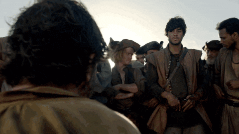 a group of men are standing in a circle and one of them has a necklace around his neck