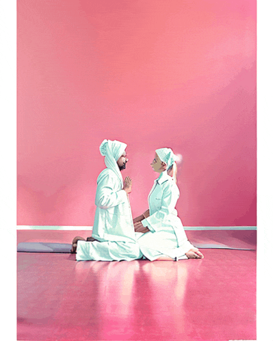 a man and a woman are kneeling in front of a pink wall and praying