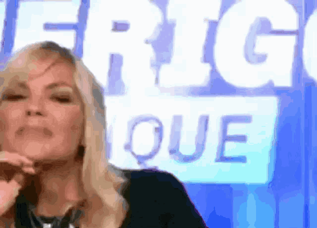 a woman stands in front of a sign that says frig que