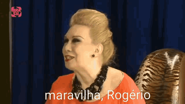 a woman sitting in a chair with the words " maravilha rogerio " on the screen