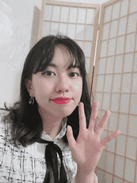 a woman with red lipstick is waving her hand in front of a screen