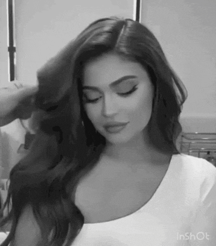 a black and white photo of a woman with long hair in a white shirt .