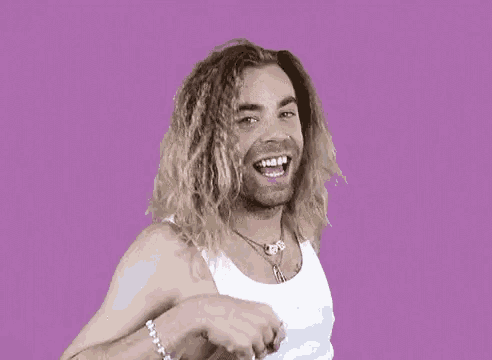 a man with long hair and a tattoo on his arm giving a peace sign
