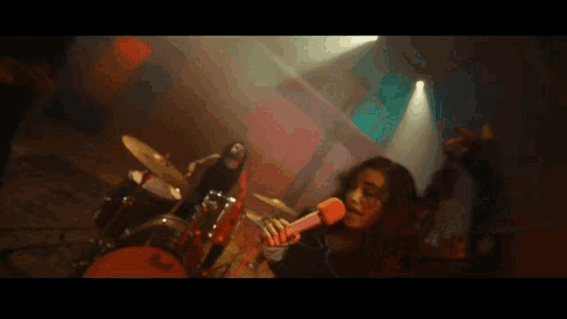a woman is singing into a microphone while a man plays a guitar
