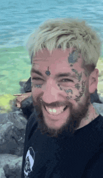 a man with tattoos on his face is smiling