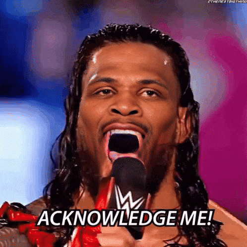 a man with long hair is holding a microphone in his mouth and saying acknowledgement me .