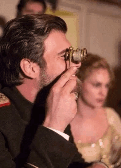 a man with a beard is holding a pair of binoculars in his hand .