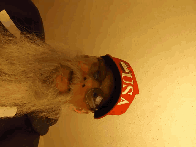 a man with a beard wears a red hat that says usa on it