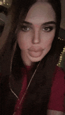 a woman wearing a red shirt is taking a selfie