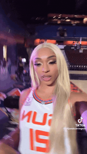 a woman with blonde hair is wearing a basketball jersey with the number 15 on it