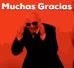 a man in a suit and tie is dancing in front of a red background that says muchas gracias on it