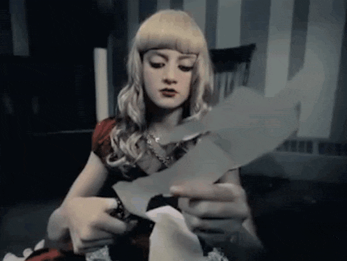 a woman with blonde hair is holding a piece of paper in her hands