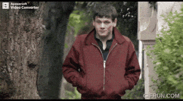 a man in a red jacket is standing in front of a tree with a powersoft video converter on the bottom of the screen