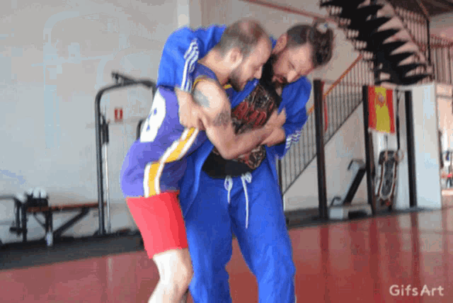 two men are wrestling in a gym with a gifs art watermark on the bottom right