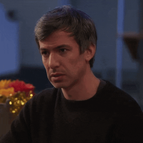 a man in a black sweater is looking at something