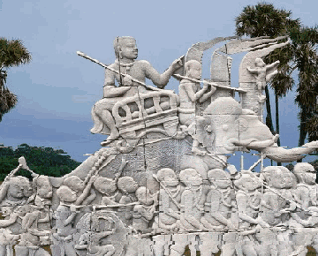 a statue of a man holding a sword is surrounded by a group of people