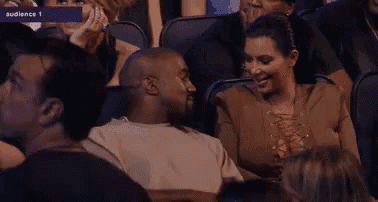 a man and a woman are sitting in a stadium and talking to each other .