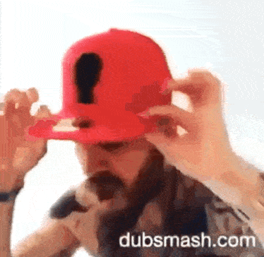 a man with a beard is wearing a red hat that says dubsmash.com on it