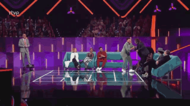 a group of people sitting on a couch on a stage with the letters rtve on the bottom