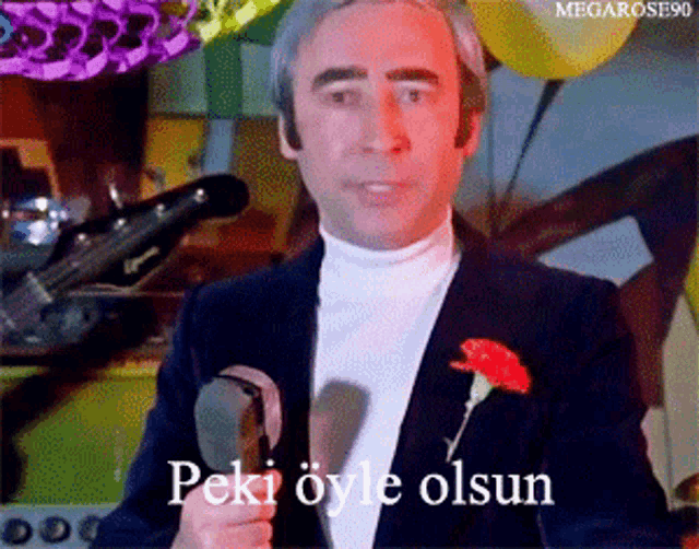 a man holding a microphone with the words peki oyle olsun written on it